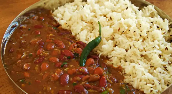 En skål med rajma chawal, en indisk rätt med kidneybönor i en kryddig sås och ris, toppad med en grön chili.