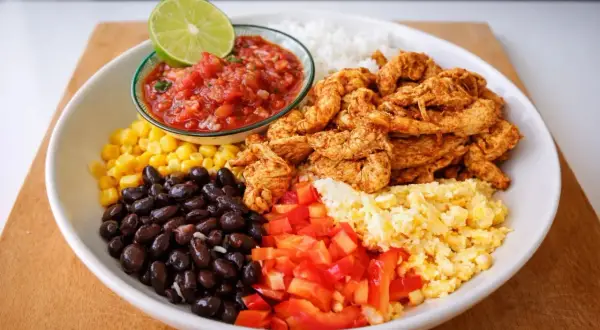 En färgglad bowl med ris, svarta bönor, majs, kyckling, salsa, lime och äggröra. Ett perfekt bowl recept för en snabb och god middag.