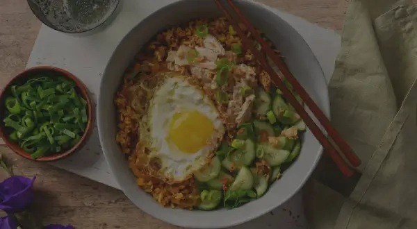 En skål med stekt ris med ett stekt ägg, kyckling och gurka. Enkel och god egg rice.
