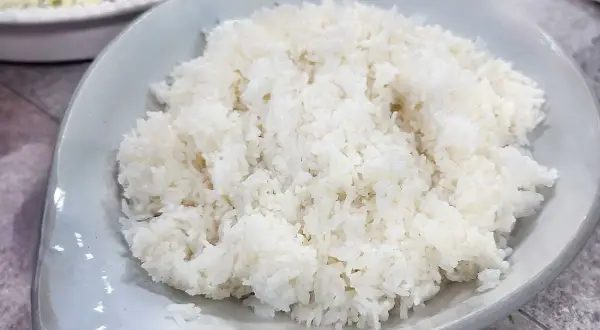 Perfekt fluffigt ris, enkelt att laga mat i riskokare. En skål med vitt ris står framför en annan skål med mat.