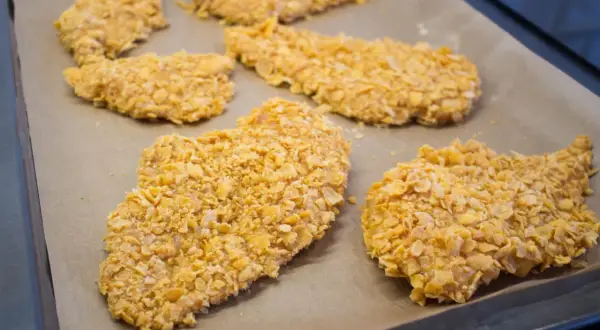 Flera bitar cornflakes kyckling ligger på en bakplåt.