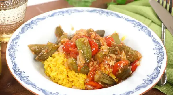 En tallrik med okra och tomater i en kryddig sås, serverad med gul ris. Ett läckert bamya recept för en smakrik måltid.