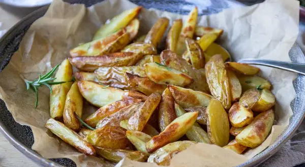 Klyftpotatis i airfryer, gyllene och krispiga, serverade med färsk rosmarin. Perfekt som tillbehör!