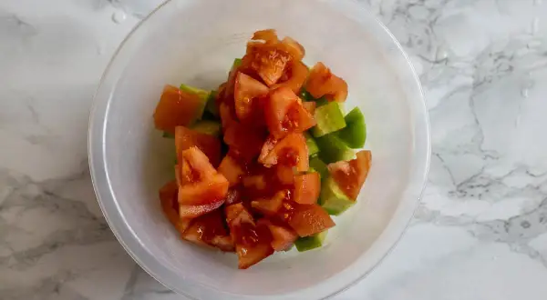 Tärnad tomat och gurka i en skål, redo att bli en fräsch sallad shirazi.