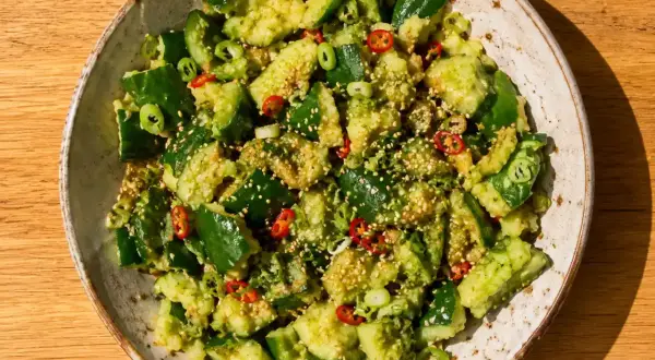 En skål med asiatisk gurksallad, toppad med sesamfrön, chili och salladslök.