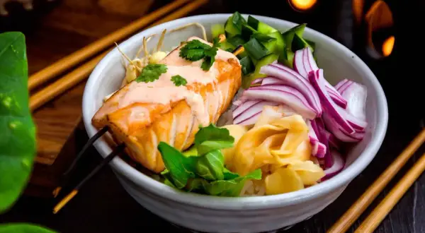 En läcker lax poke-bowl med ris, gurka, rödlök och ingefära. En krämig sås toppar den saftiga laxfilén.