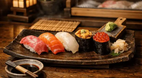 En vacker tallrik med olika sushi, inklusive nigiri med tonfisk och lax, samt gunkanmaki med havsborre och rom. Dessa risrätter ser utsökta ut.