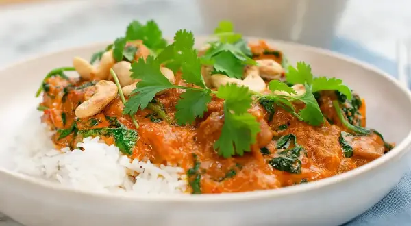 En krämig palak chicken med ris, toppad med cashewnötter och färsk koriander. En smakrik indisk rätt.