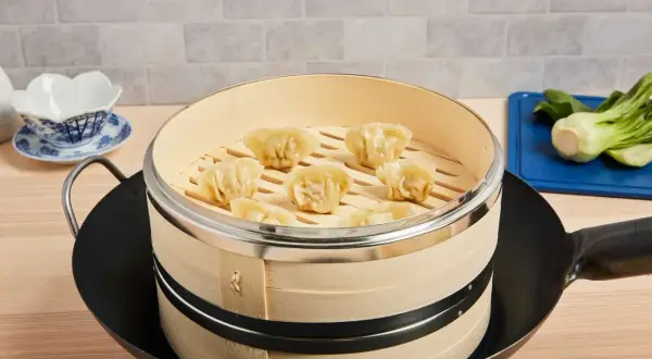 Färdiga dumplings i bambuångare, redo att serveras. Lär dig hur du använder en steamer för perfekta dumplings.