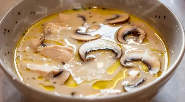 En ångande skål med krämig tom kha gai, fylld med möra kycklingbitar och saftiga champinjoner.