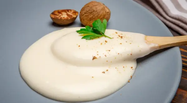 Krämig bechamelsås på en tallrik, med muskotnötter och persilja. Perfekt för att frysa in och använda senare.