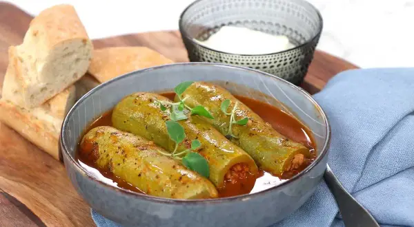 Kousa mahshi, fyllda squash i en mustig tomatsås, serveras med färskt bröd och en skål yoghurt.