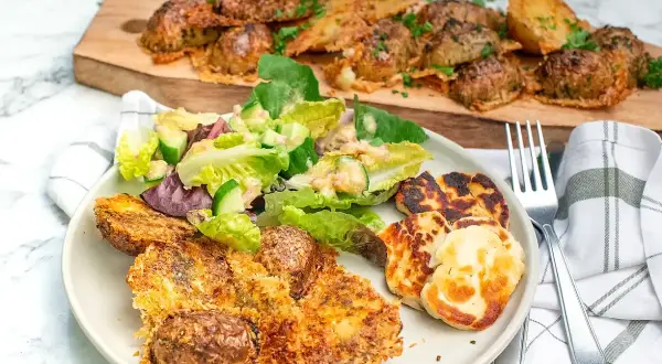 Krispiga, ugnsbakade potatisar med ostpanering serveras med en fräsch sallad och grillad halloumi. En härlig måltid!