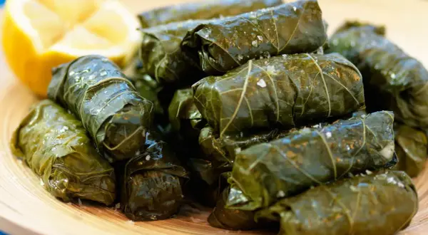 En hög med sarma, vindruveblad fyllda med ris och kryddor, serveras med en citronklyfta. Ett utsökt sarma recept!
