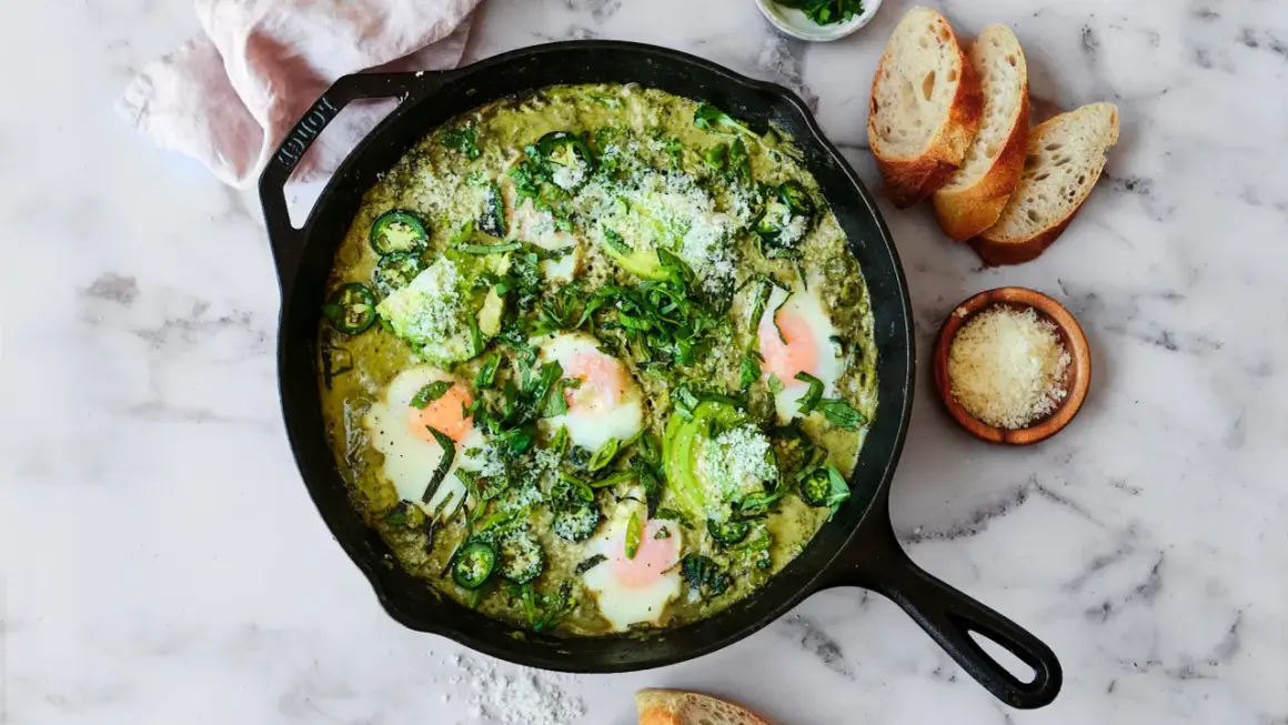 Grön shakshuka med ägg, avokado och jalapeño i gjutjärnspanna. Perfekt för ett smakrikt shakshuka recept.