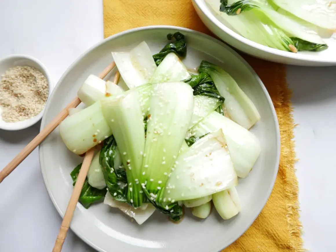 Enkel pak choi recept med sesamfrön. Grönsakerna är serverade på en tallrik med ätpinnar.