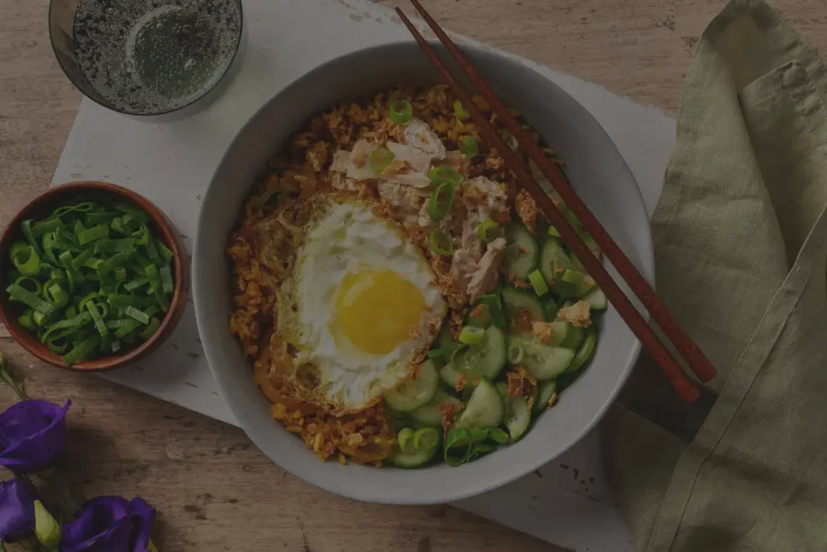 En skål med stekt ris med ett stekt ägg, kyckling och gurka. Enkel och god egg rice.