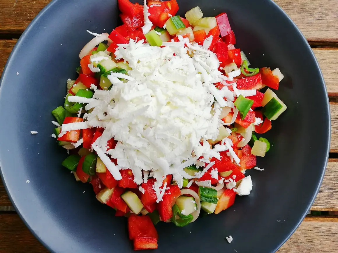 En fräsch sopska salata med hackad tomat, gurka, paprika och lök, toppad med riven ost.
