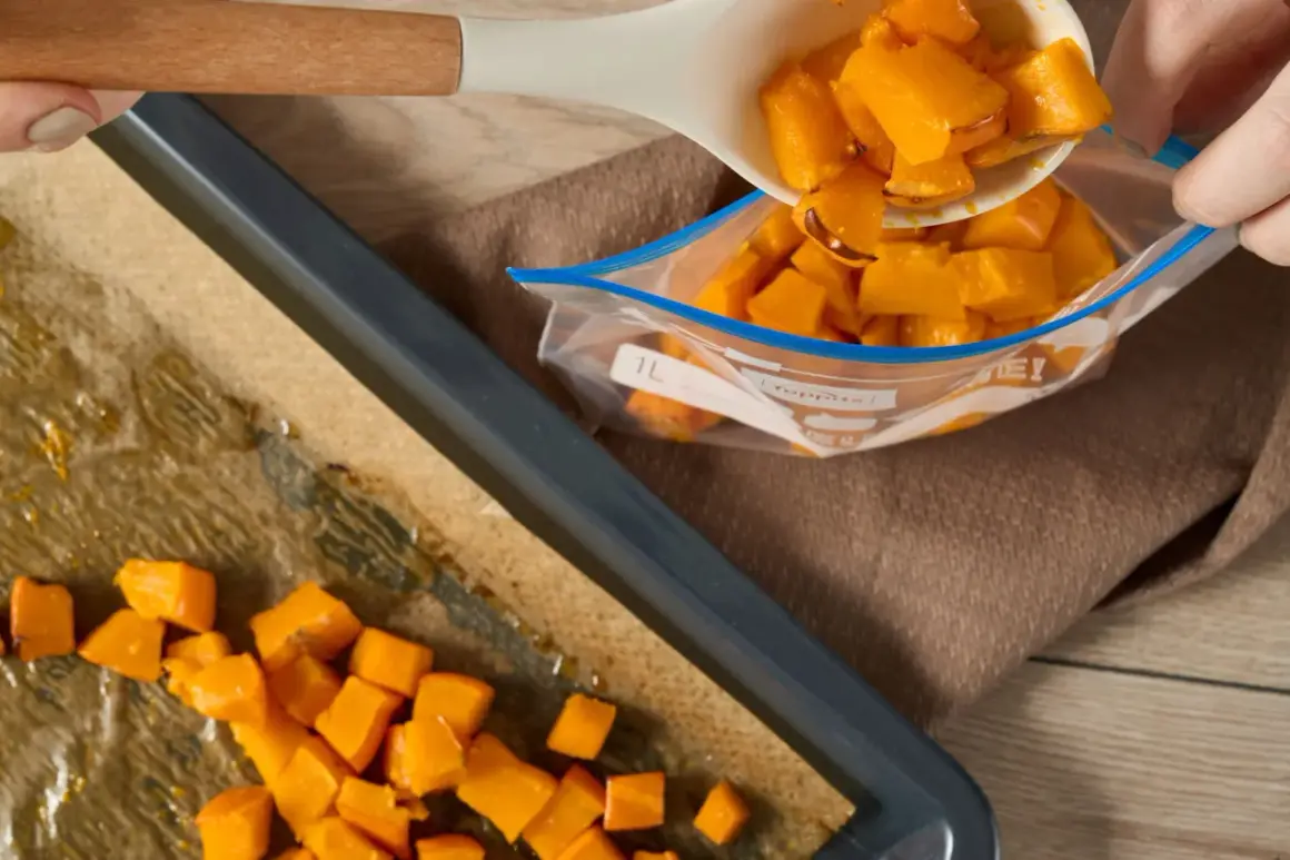 Förbereder butternutpumpa för ett recept. Tärnad pumpa läggs från en sked till en fryspåse.
