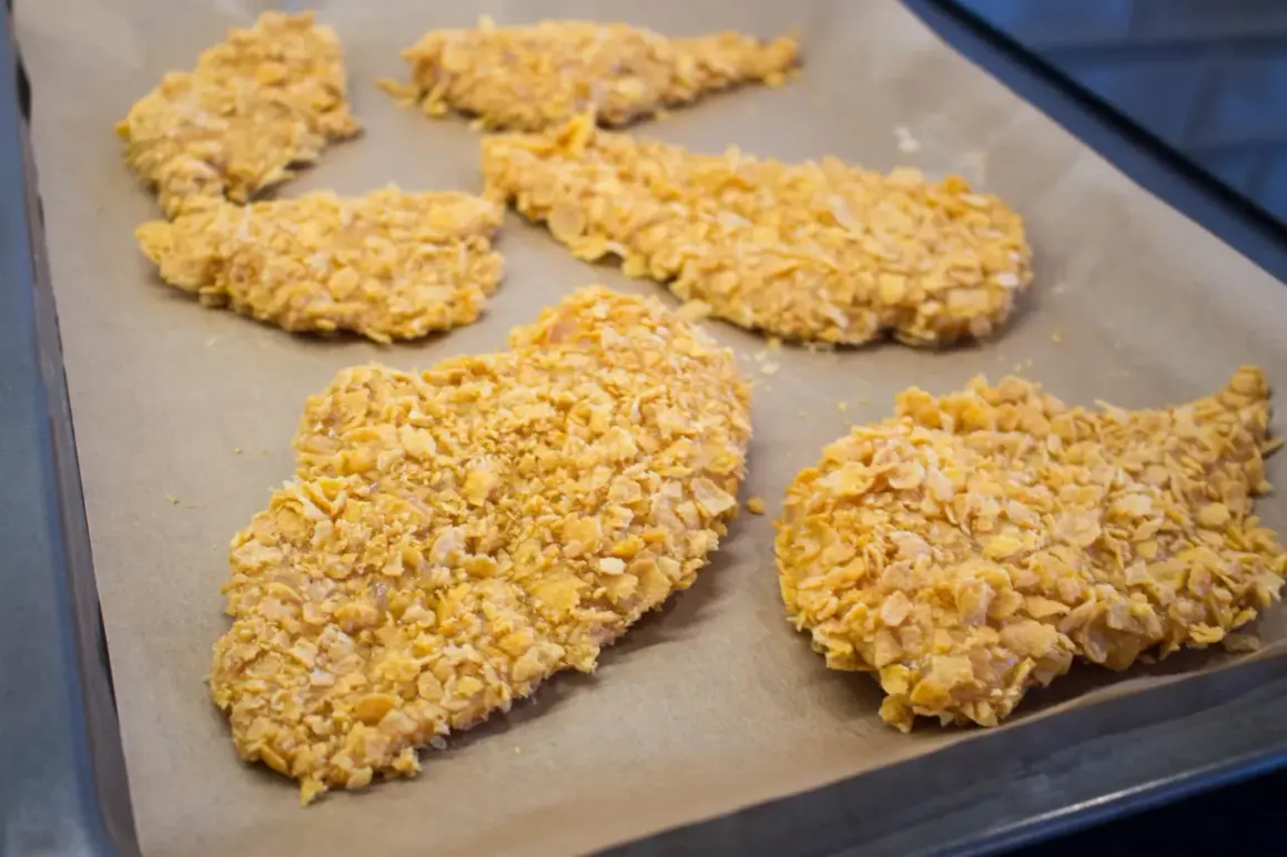 Flera bitar cornflakes kyckling ligger på en bakplåt.