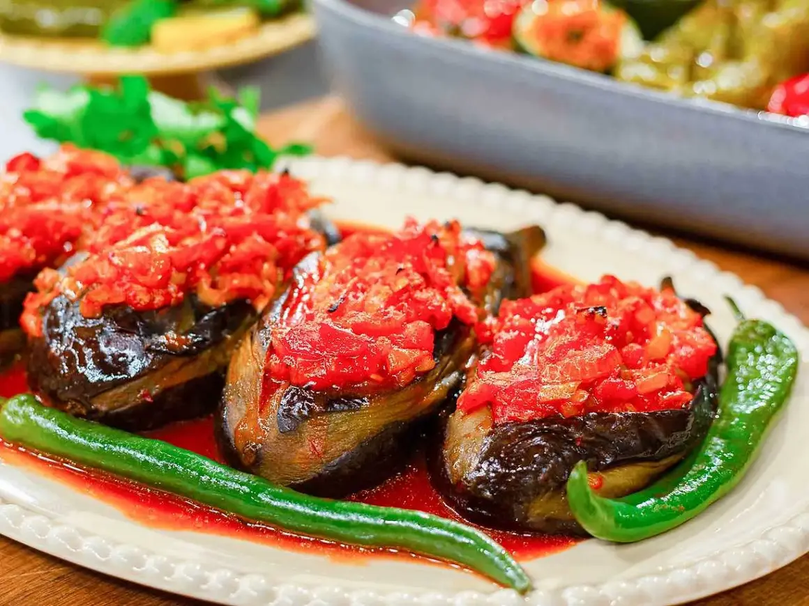 Tre auberginehalvor fyllda med tomat och paprika, serverade med gröna chilis. En härlig imam bayildi.