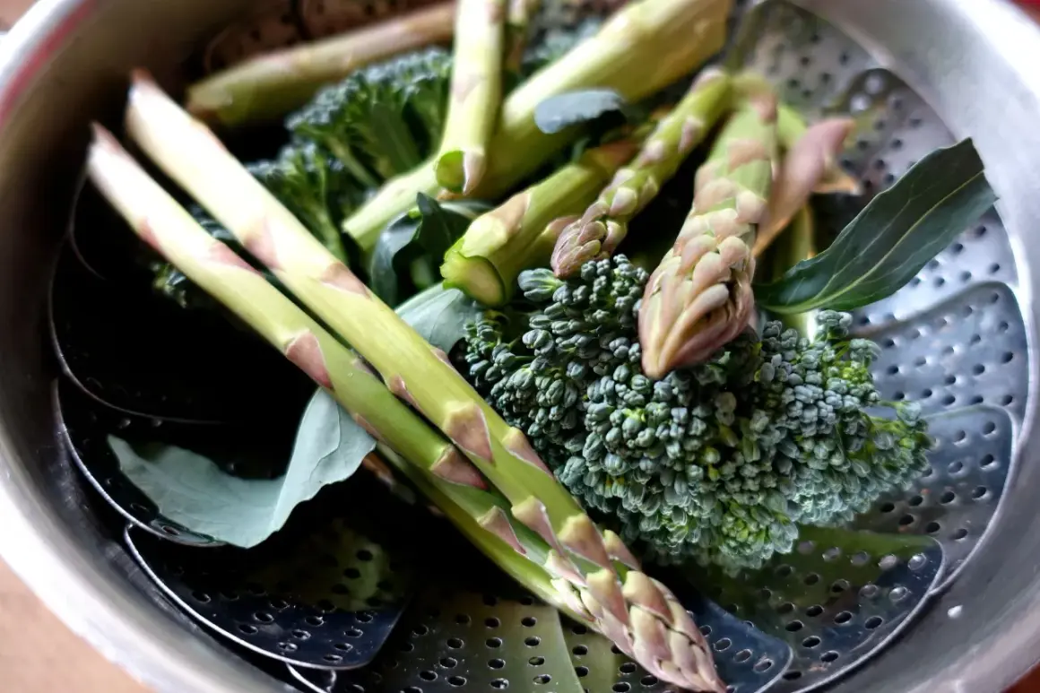 Grön sparris och broccoli ligger i en ångkorg, redo att ångkokas till perfektion.