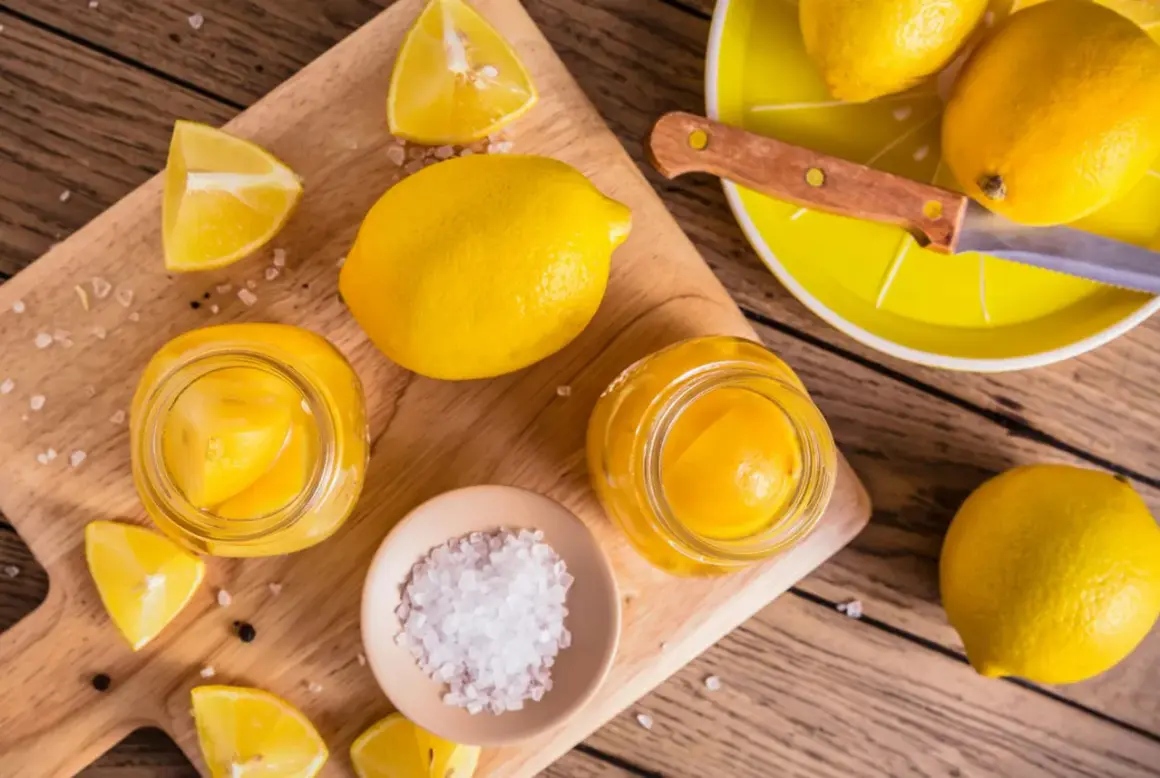 Gör ett läckert recept med inlagda citroner! Färska citroner, salt och pepparkorn förbereds på en träskärbräda.