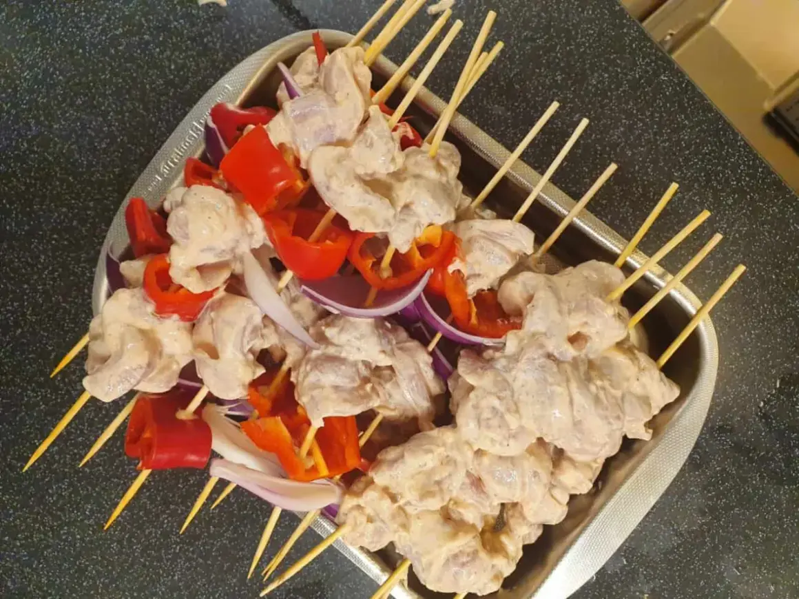 Shish tawook-spett på spett med kyckling, röd paprika och lök, redo att grillas.