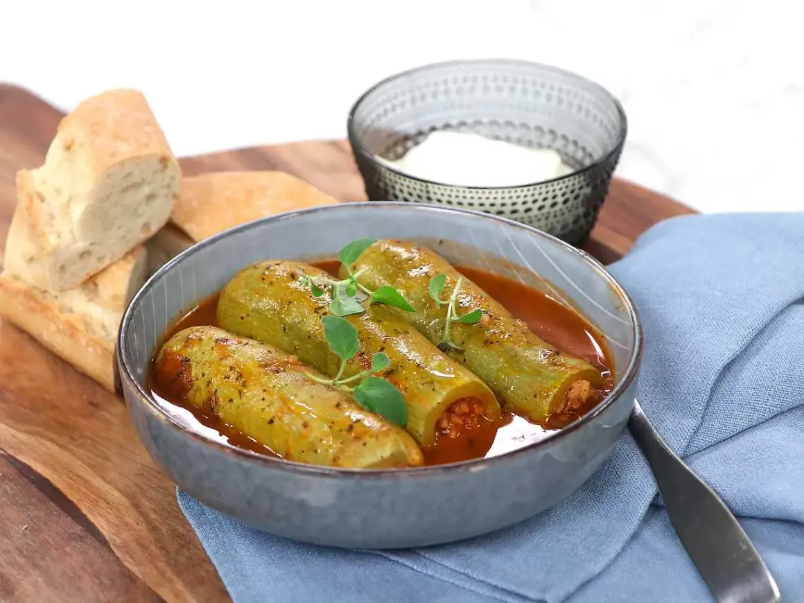 Kousa mahshi, fyllda squash i en mustig tomatsås, serveras med färskt bröd och en skål yoghurt.