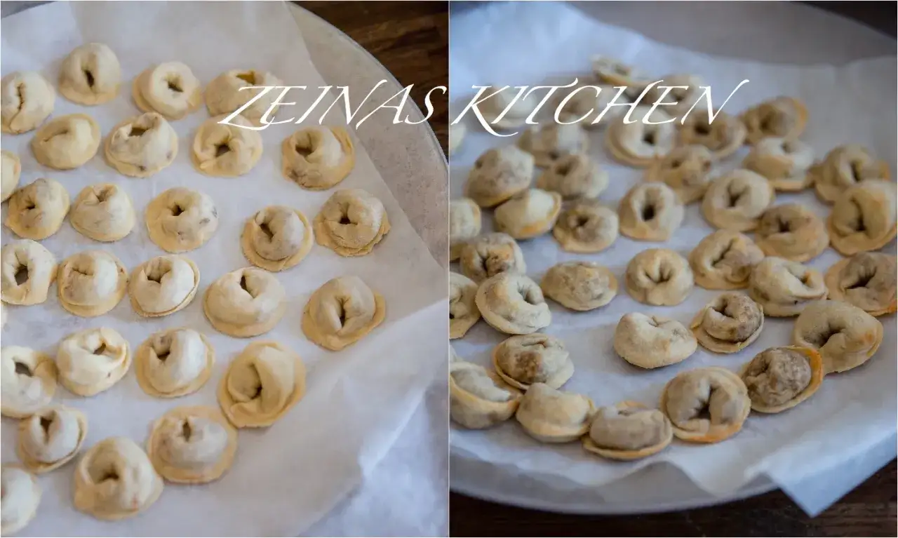 Sm&aring;, runda shish barak-dumplings ligger utspridda p&aring; bakpl&aring;tspapper, redo att tillagas.
