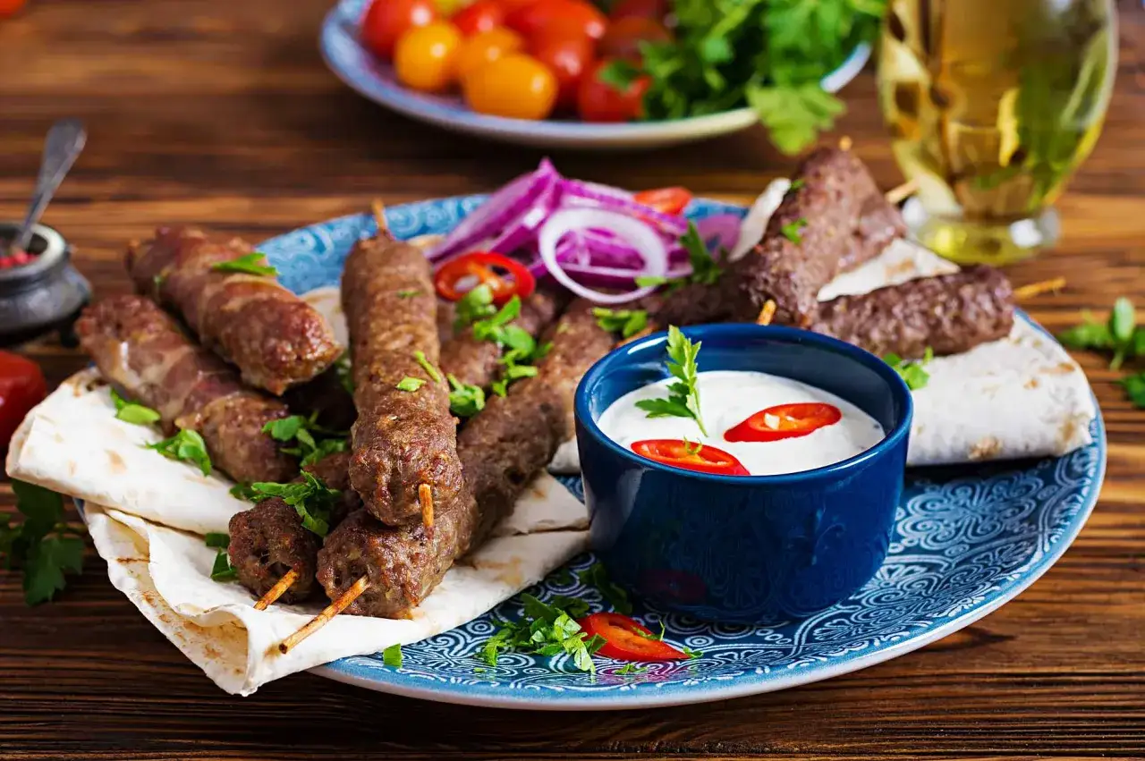 Kofta p&aring; spett med pitabr&ouml;d, r&ouml;dl&ouml;k och en kr&auml;mig vit kebabs&aring;s med chili.