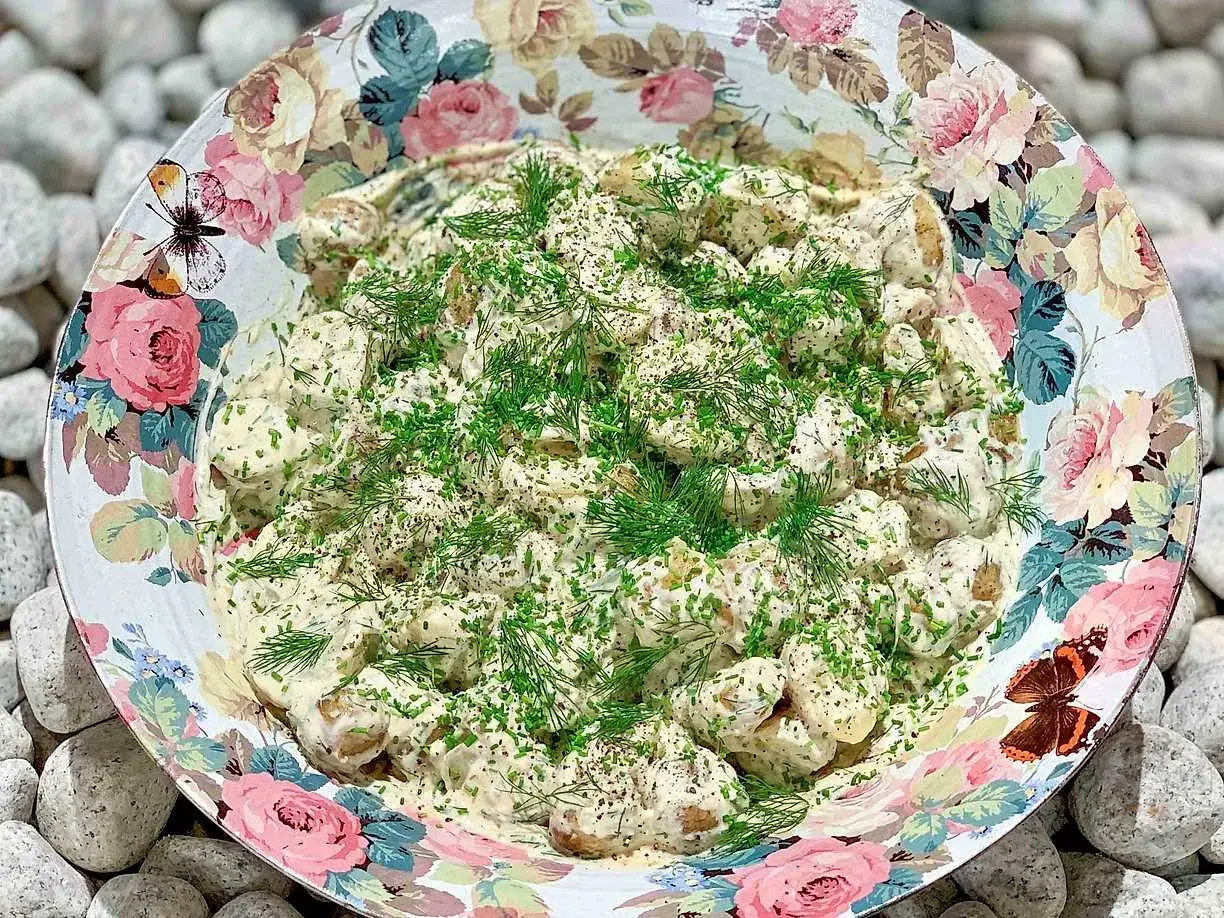 Krämig potatissallad med dill och gräslök i en vacker skål. Ett perfekt potatis recept för sommaren.