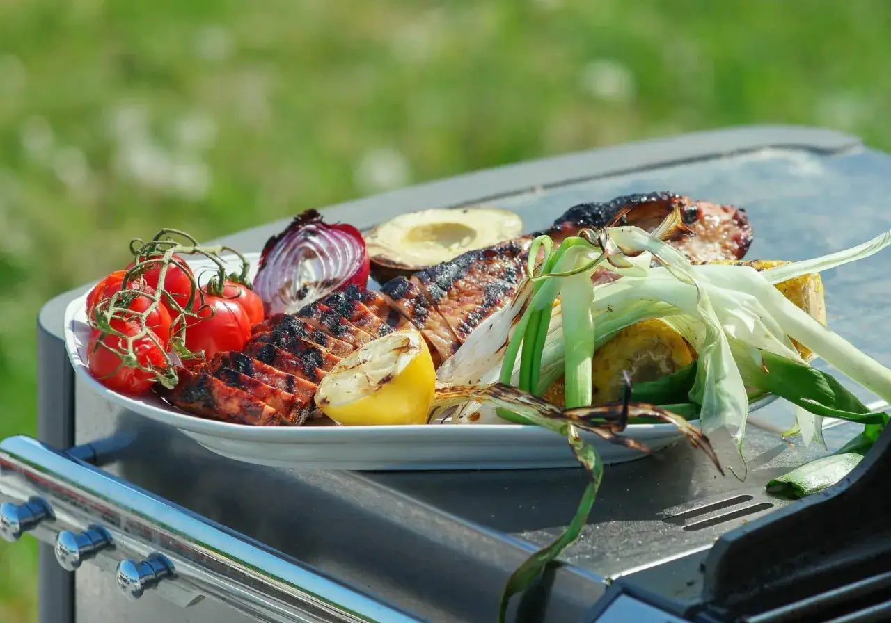 En tallrik med grillad mat, inklusive kött, tomater, lök, majs och citron, redo för grillens dag.