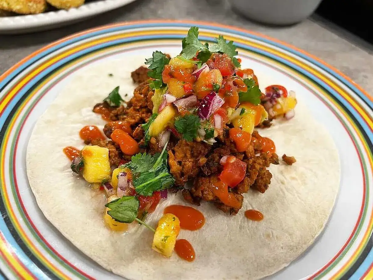 En taco med kryddig tacokrydda, ananas, tomat och koriander. Perfekt för en snabb middag!