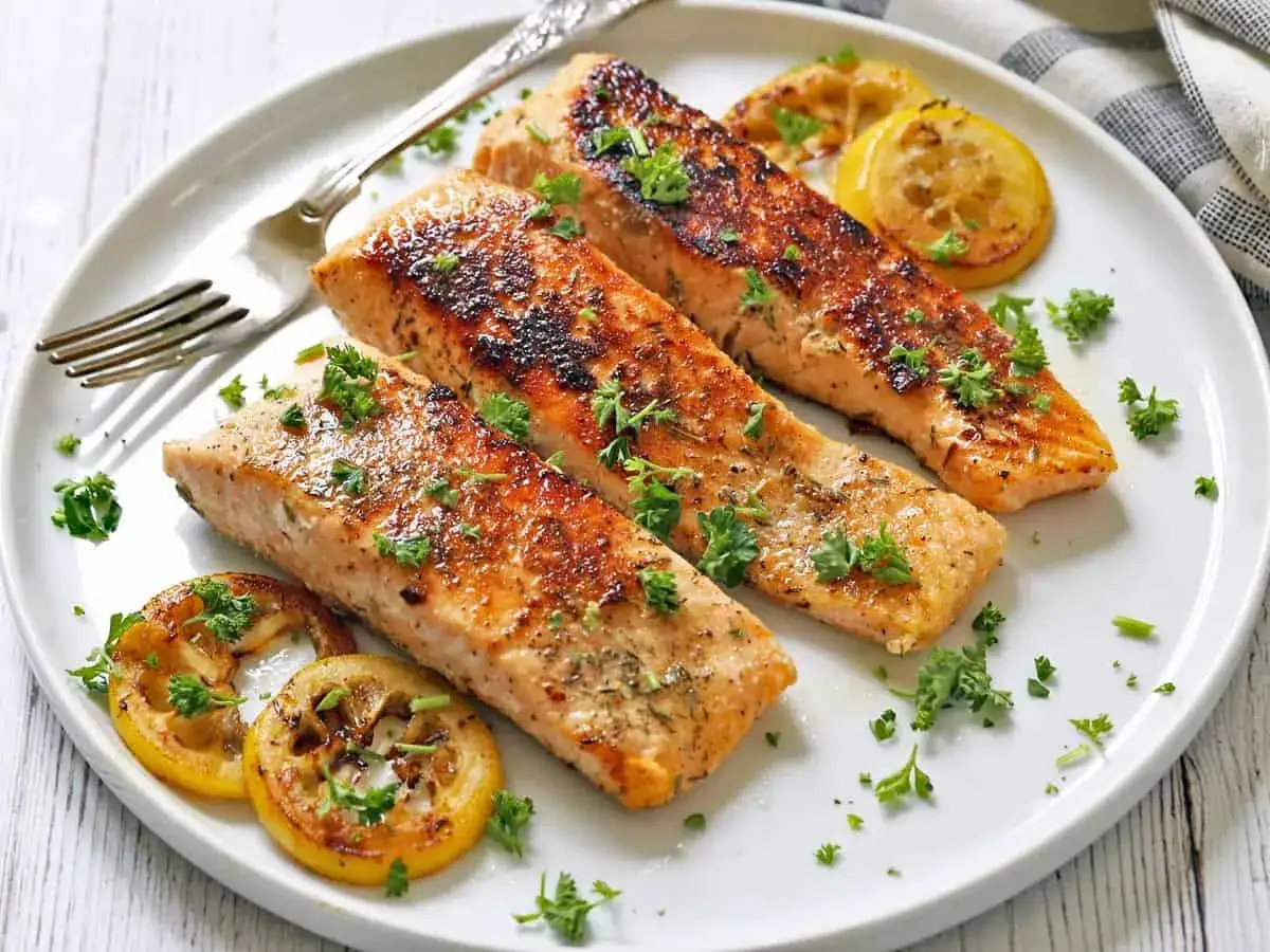 Tre saftiga laxfiléer, perfekt stekta med krispig yta, garnerade med persilja och citron. Ett underbart lax recept för en härlig måltid.