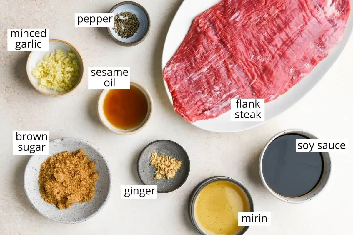 Rå flankstek med ingredienser för en enkel marinad: vitlök, peppar, sesamolja, farinsocker, ingefära, mirin och sojasås.