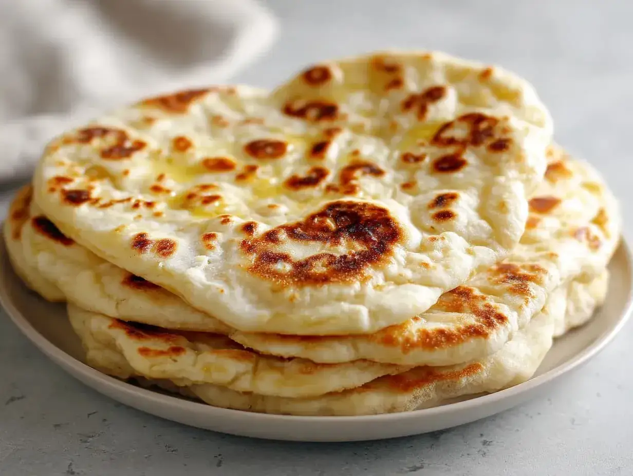 En h&ouml;g med nybakade, gyllene naanbr&ouml;d, perfekt f&ouml;r ditt n&auml;sta naan recept. Sm&auml;lt sm&ouml;r gl&auml;nser p&aring; ytan.