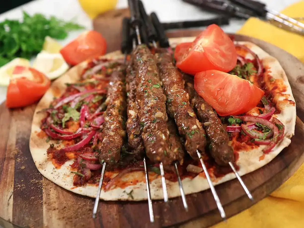 Saftiga kebabspett i ugn serveras på tunnbröd med rödlök, tomat och persilja. En härlig måltid!