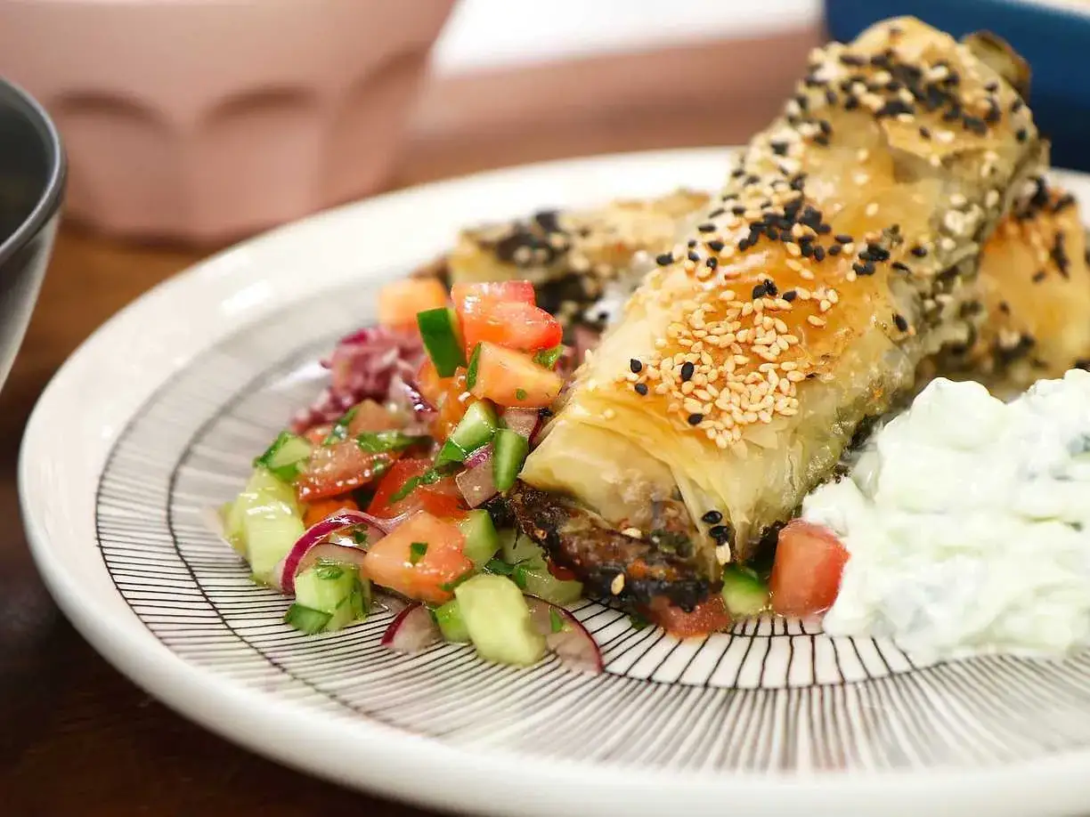 Krispiga filodegsrullar med sesamfrön, serverade med en fräsch tomatsallad och yoghurt. Ett utsökt burek recept!