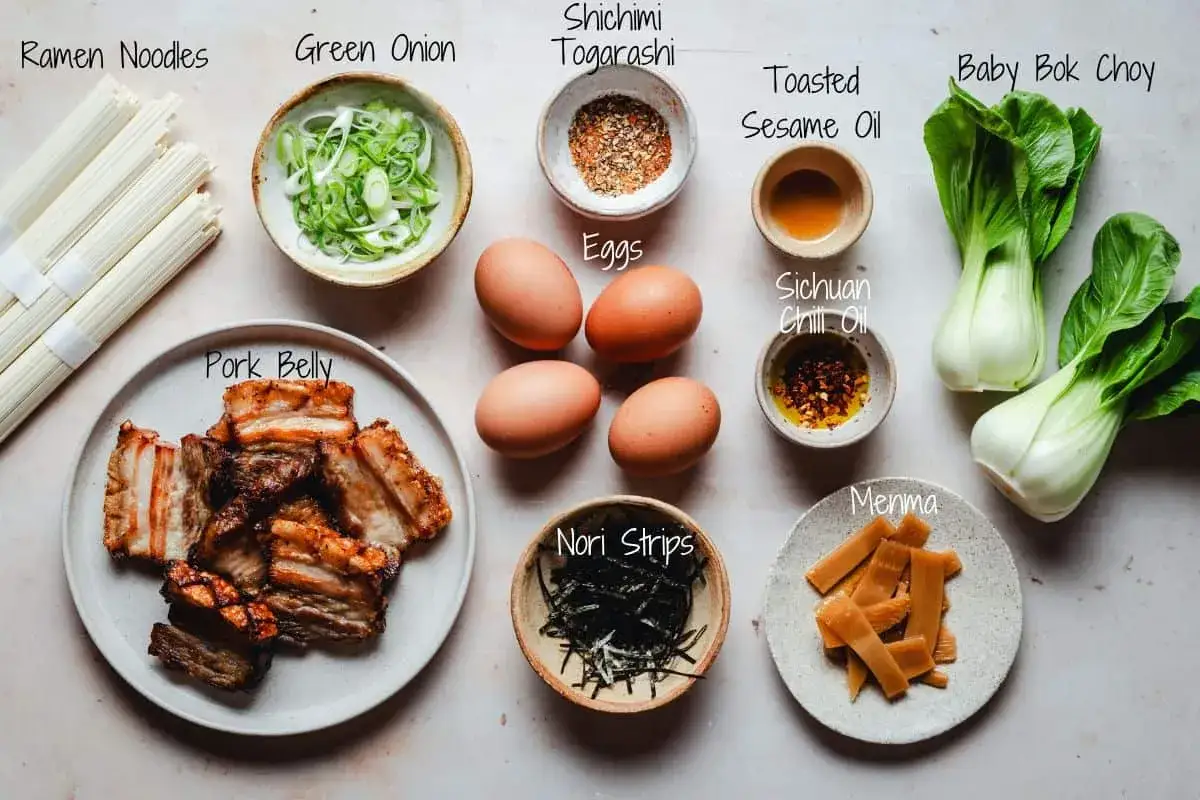 Ingredients for shoyu ramen: pork belly, ramen noodles, eggs, bok choy, green onion, menma, nori, and spices.