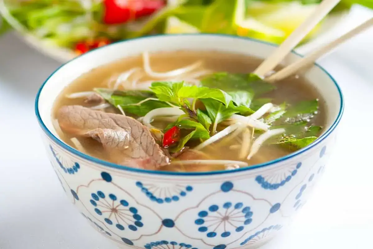 En skål med pho recept, med nudlar, biff, böngroddar och färska örter. En klassisk vietnamesisk rätt.