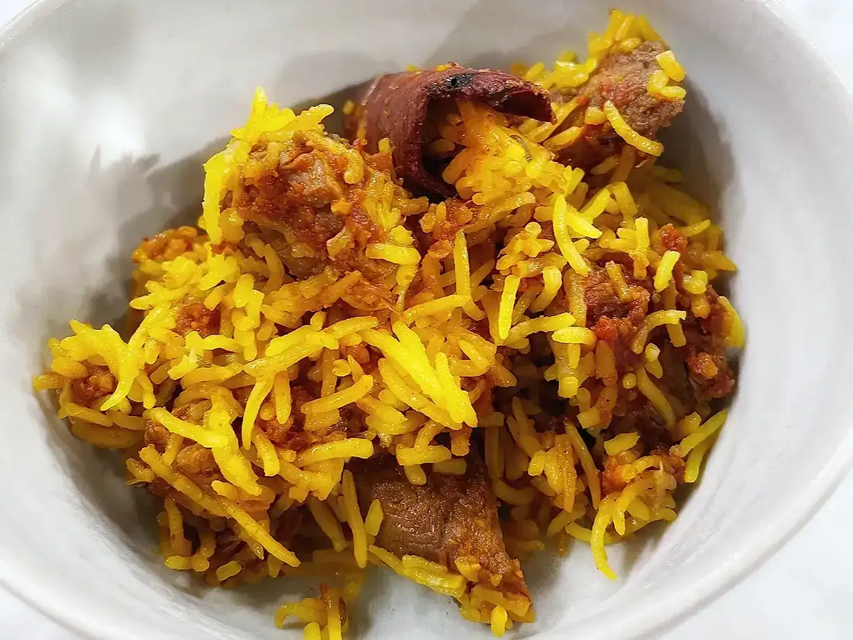 En sk&aring;l med gyllene ris och m&ouml;ra bitar av lammk&ouml;tt, en h&auml;rlig lamm biryani.