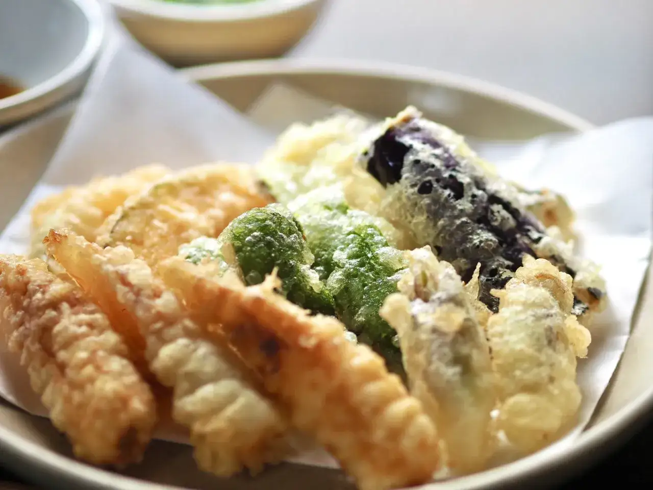 En tallrik med krispig tempura, där grönsaker och räkor badar i en lätt tempura smet.