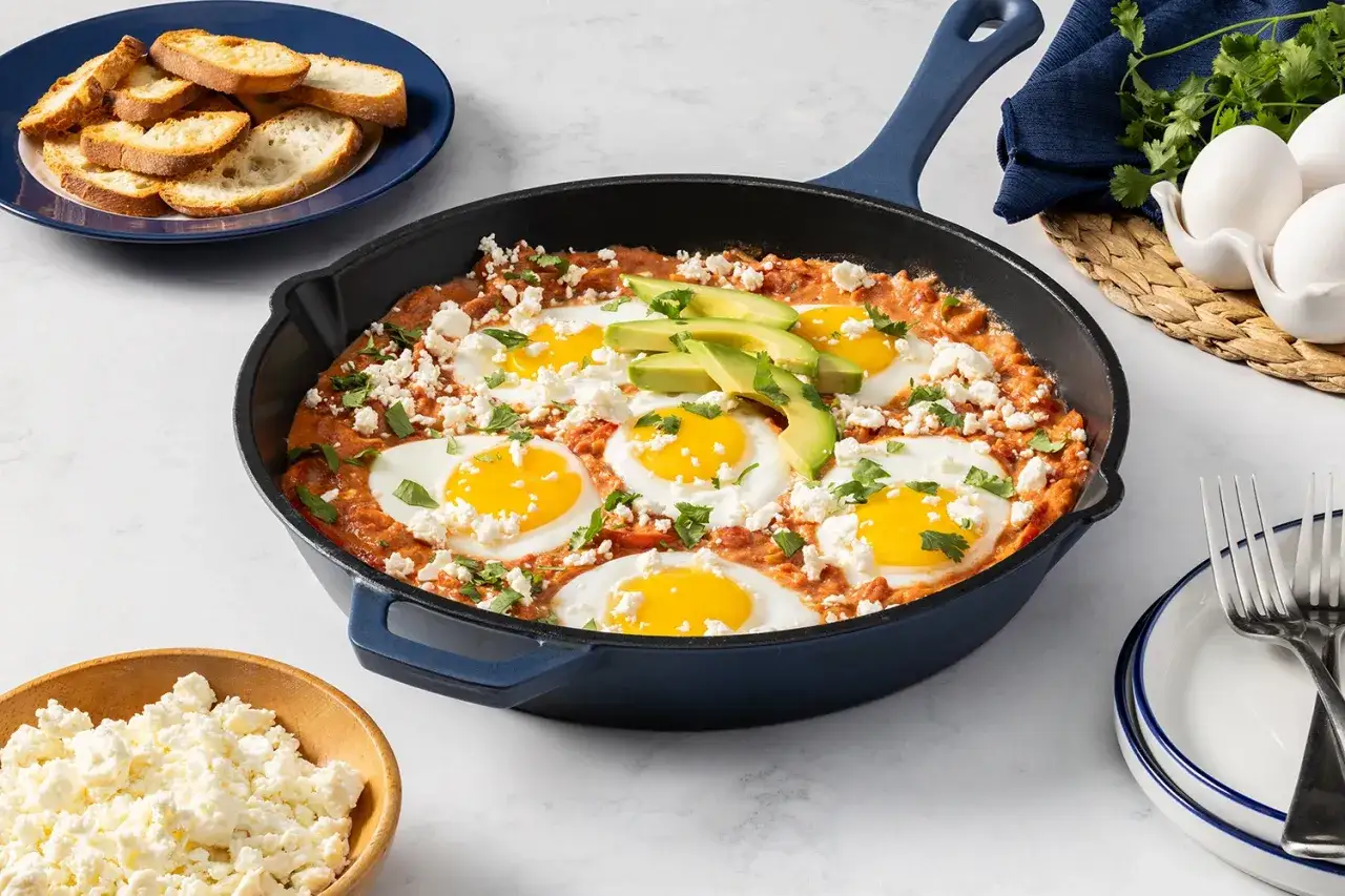 En smakrik shakshuka med ägg, avokado och fetaost i en gjutjärnspanna. Perfekt för ett mysigt frukostrecept.