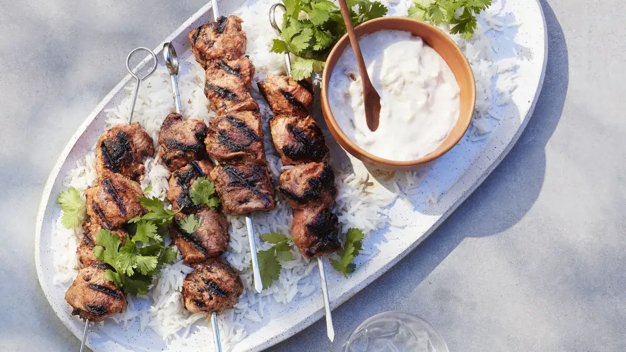 Grillade spett med shish tawook, serverade p&aring; en b&auml;dd av ris med en sk&aring;l yoghurt och f&auml;rsk koriander.