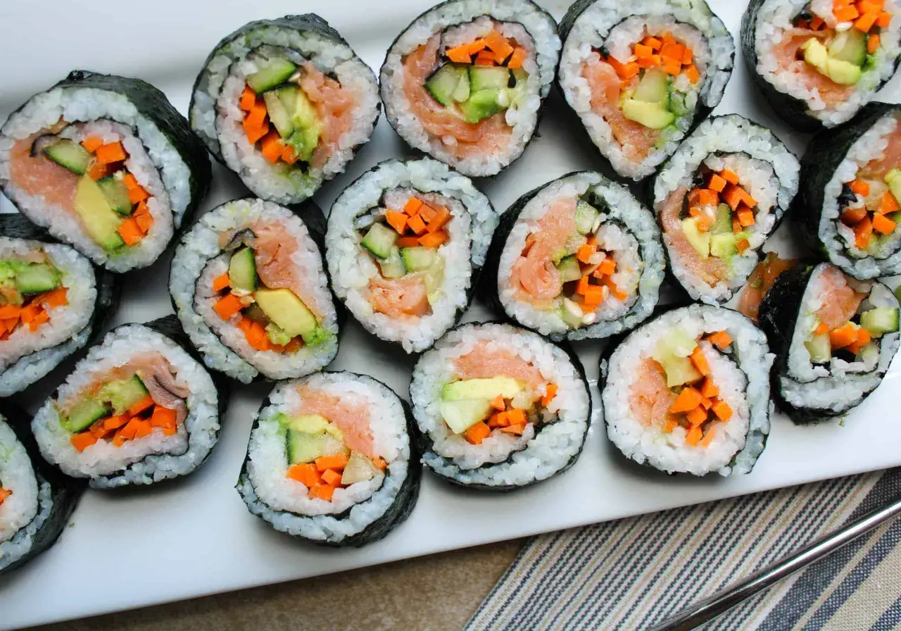 En tallrik med sushi-rullar fyllda med lax, gurka och morot. Dessa sushi ingredienser ser aptitliga ut.