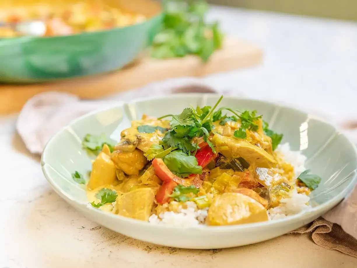 En krämig kycklingcurry med ris, toppad med färsk koriander. En riktig curry nam nam!