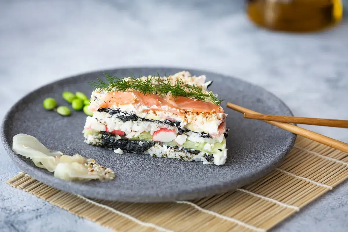 En bit av en vacker sushi t&aring;rta med lax, ris, alger och gr&ouml;nsaker. Serveras med edamameb&ouml;nor och ingef&auml;ra.