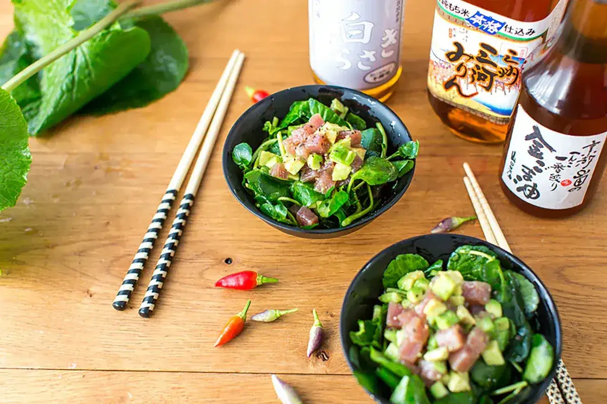 Tv&aring; sk&aring;lar med poke bowl, avokado och tonfisk. Flera flaskor med japanska s&aring;ser, inklusive en med texten 
