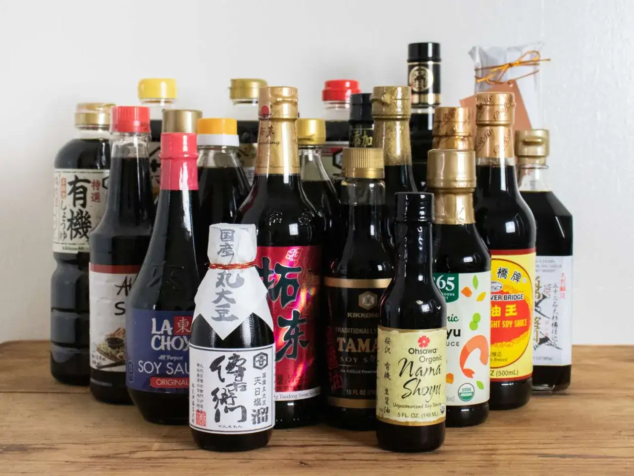 En samling flaskor med asiatisk sojasås, från små till stora, med olika etiketter och färger.